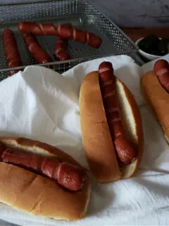 Perfectly cooked hot dog wieners in the air fryer served on hot dog buns with toppings