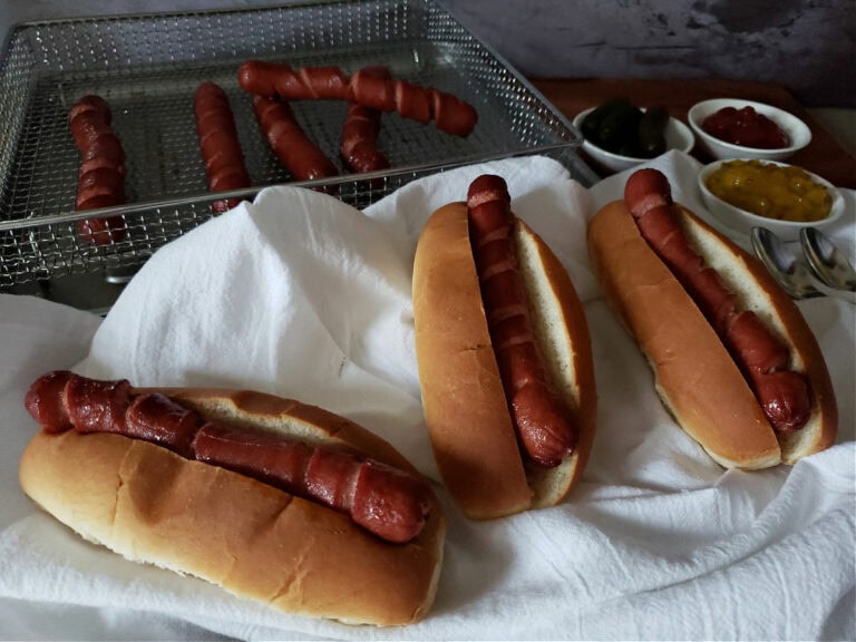 Perfectly cooked hot dog wieners in the air fryer served on hot dog buns with toppings