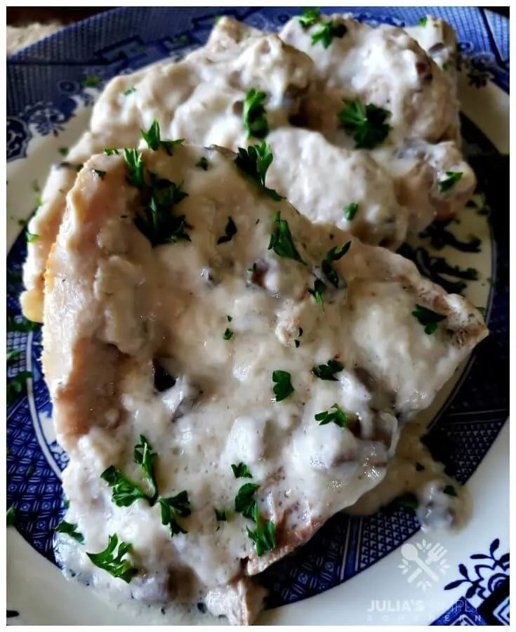 Tender baked pork chops smothered in cream of mushroom soup recipe garnished with parsley