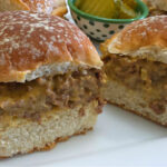 White platter with Easy Cheesy Loose Meat Sliders Recipe with a side of pickle slices