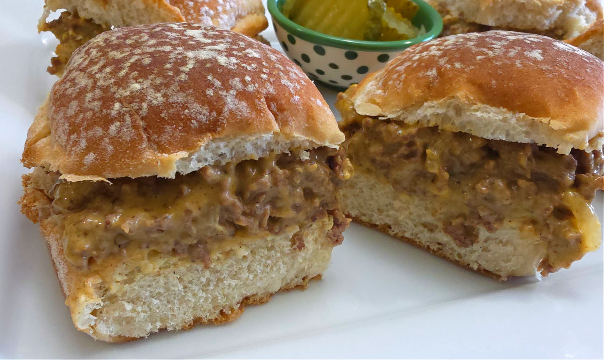 White platter with Easy Cheesy Loose Meat Sliders Recipe with a side of pickle slices