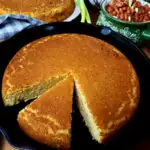 Easy Southern Cornbread recipe without buttermilk in a cast iron skillet with pinto beans in the background