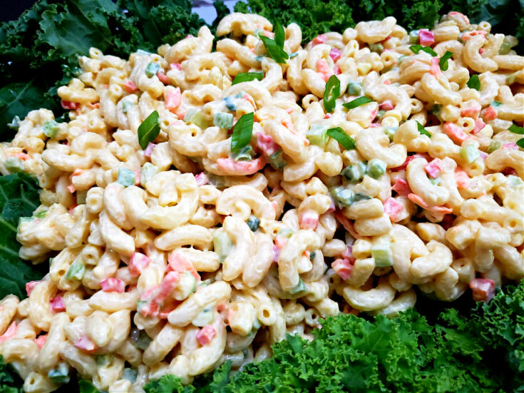 The Best Classic Macaroni Salad Recipe on a white serving platter garnished with fresh greens and scallions