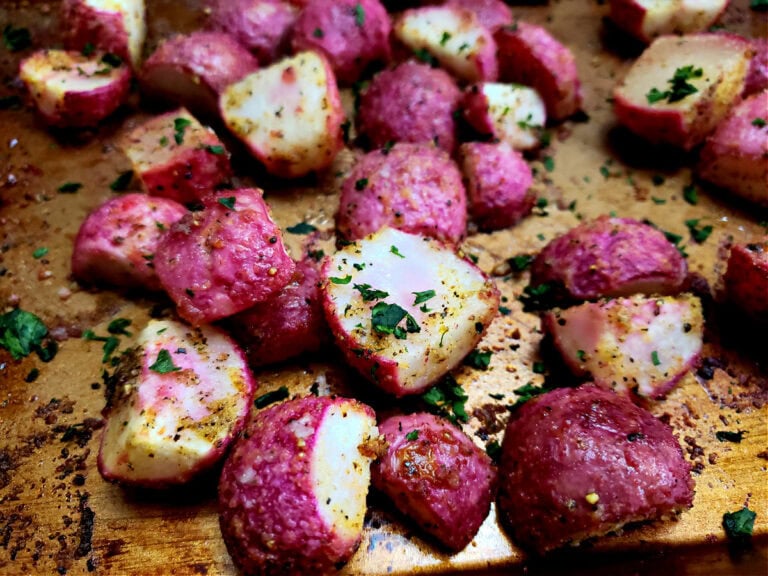 Easy roasted radishes recipe arranged on a copper colored sheet pan and garnished with parsley