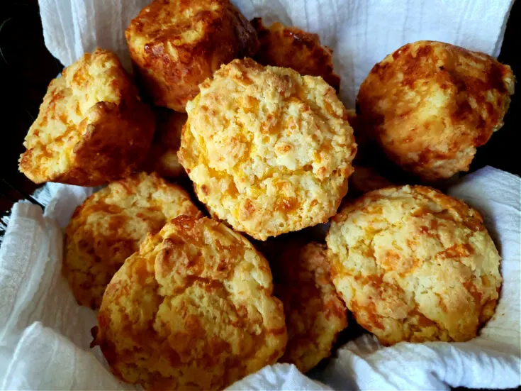 Easy Sour Cream Cheddar Cheese Biscuits Recipe in a bread basket wrapped in a white flour sack towel