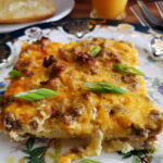 A serving of baked make ahead breakfast casserole on a Biltmore China plate with a slice of toast and orange juice