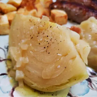 the best old fashioned southern boiled cabbage recipe on a cotton boll pattern plate with fried potatoes and sausages