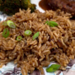 Beefy baked rice side dish on a plate served with hamburger steaks and steamed broccoli