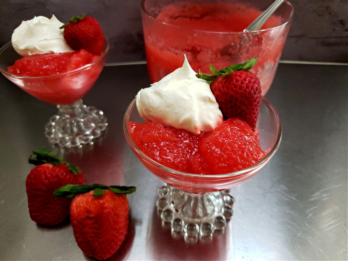 Old Timey Applesauce Salad Recipe with Jello and 7-Up served in a glass dessert dish with whipped topping and a fresh strawberry garnish