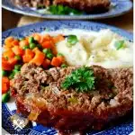 Classic Southern Meatloaf Recipe on a blue and white plate with mashed potatoes and peas and carrots