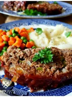 Classic Southern Meatloaf Recipe on a blue and white plate with mashed potatoes and peas and carrots