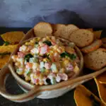 cold corn dip served in a serving bowl with tortilla chips and bagel chips
