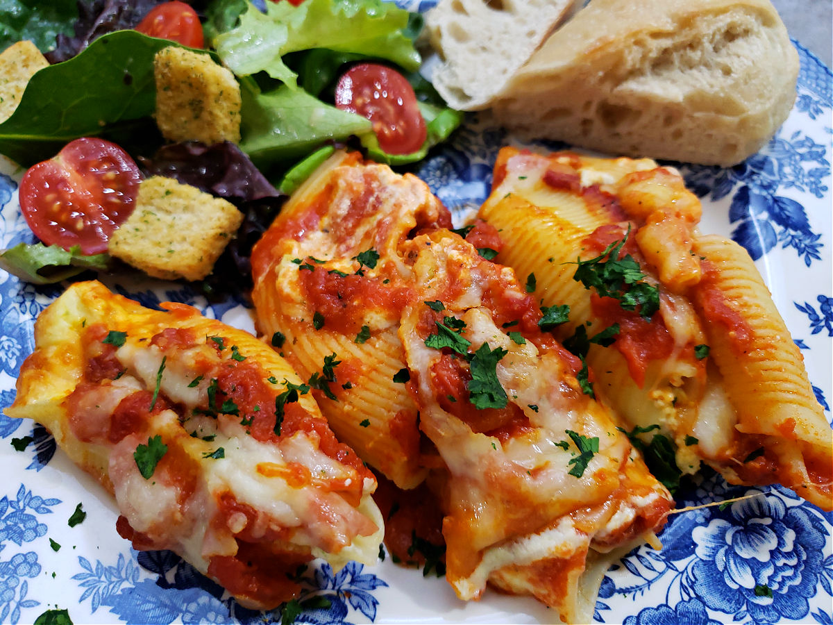 simple stuffed shells recipe with ricotta cheese served on a blue and white plate with a side salad and bread