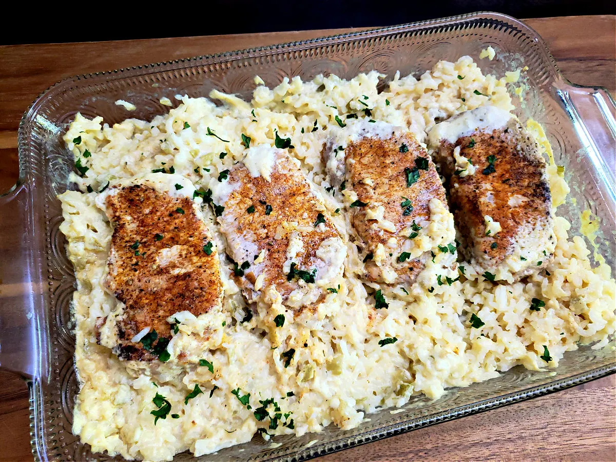 Easy baked pork chops and rice casserole recipe in a glass baking dish garnished with chopped parsley
