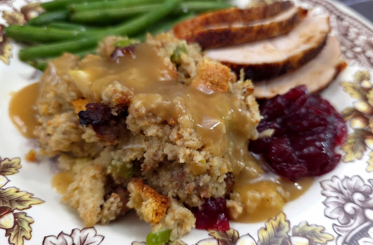 Southern Sausage, Apple, and Sage Cornbread Dressing served with turkey and string beans on a Thanksgiving plate