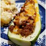 Blue and White plate with Sausage stuffed zucchini served with a side of potato salad