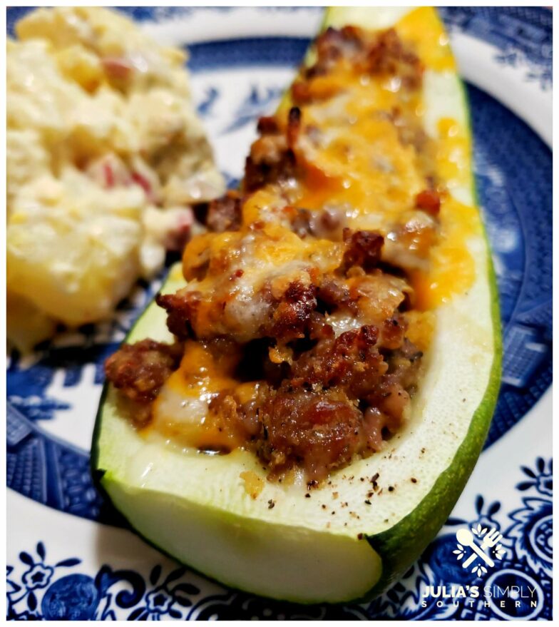 Blue and White plate with Sausage stuffed zucchini served with a side of potato salad