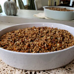 Sweet Potato Soufflé in w white oval casserole dish sitting on a buffet table with a mirror