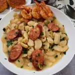 Down Home Southern Large Lima Butter Beans Recipe with slices of Andouille sausage and shrimp in a white bowl served with cornbread muffins