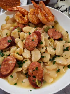 Down Home Southern Large Lima Butter Beans Recipe with slices of Andouille sausage and shrimp in a white bowl served with cornbread muffins