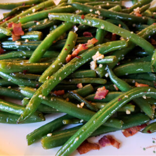 A platter with fresh sautéed green beans in a sweet and spicy sauce with garlic and bacon