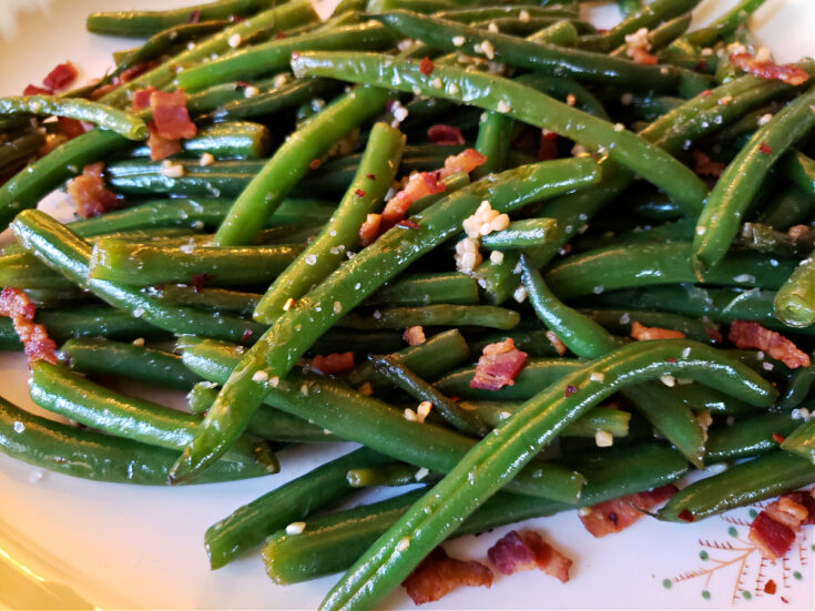 A platter with fresh sautéed green beans in a sweet and spicy sauce with garlic and bacon