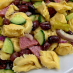 A plate of pasta salad with Salami, cucumbers and olives. Summer Tortellini Pasta Salad Recipe with Salami