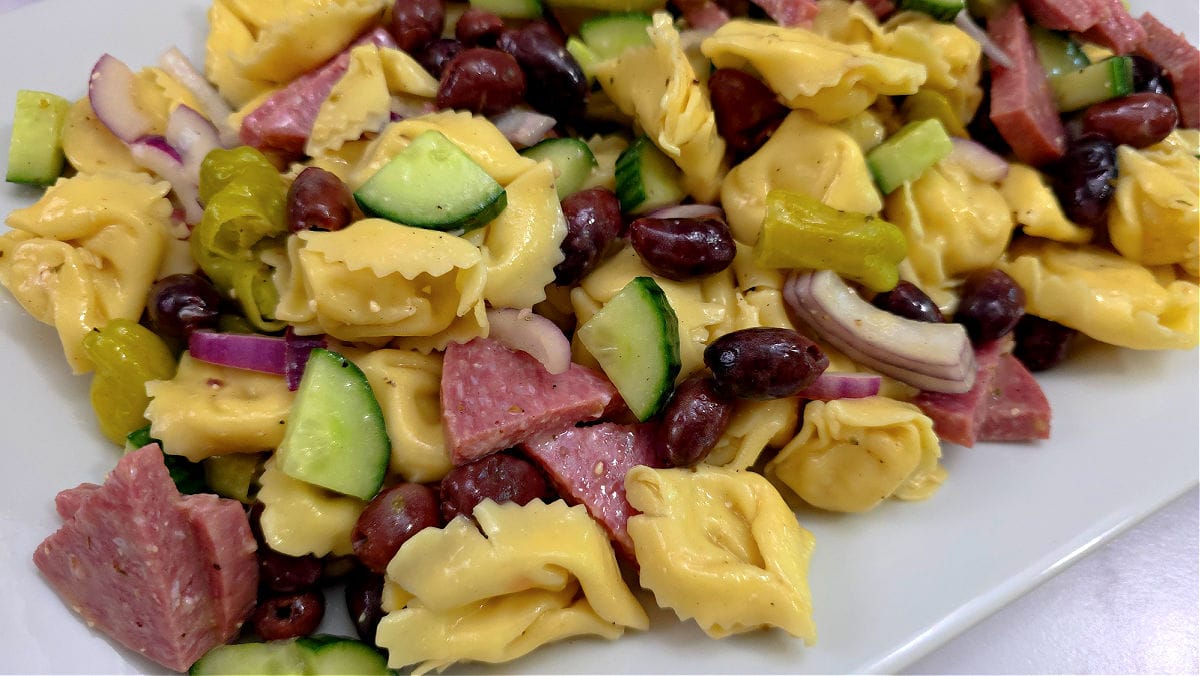 A plate of pasta salad with Salami, cucumbers and olives. Summer Tortellini Pasta Salad Recipe with Salami