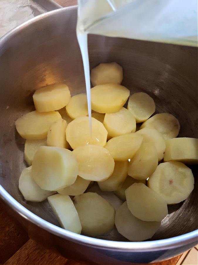 pouring duck fat over potatoes for roasting