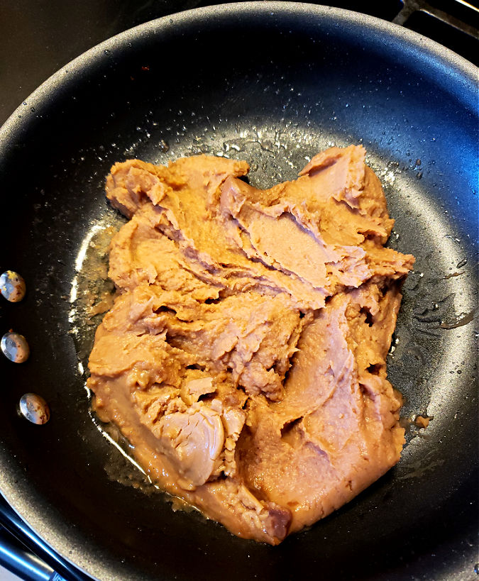 Restaurant refried beans with bacon fat in a skillet