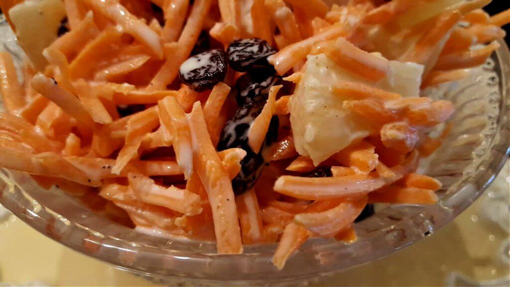 carrot raisin salad side dish in a glass serving bowl