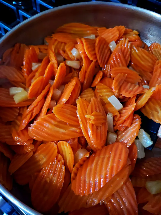 combining pineapple and carrots with glaze in a large skillet