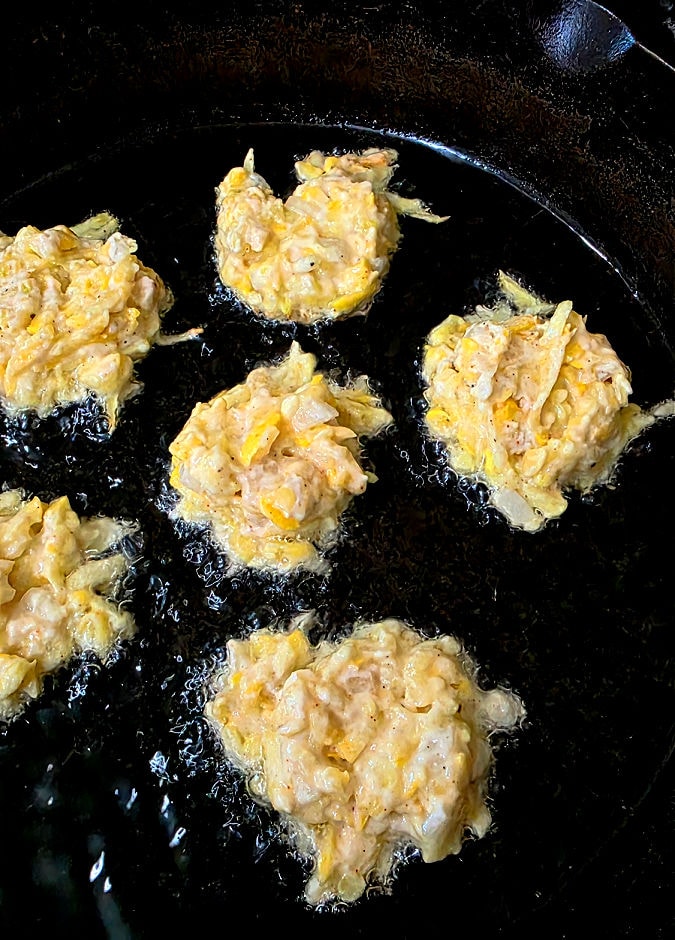 Cast iron skillet with oil frying squash fritters