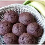 basket with chocolate banana muffins next to a bunch of fresh bananas