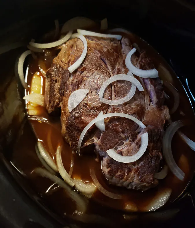 Crock Pot Barbecue chuck roast in liquid with sliced onions