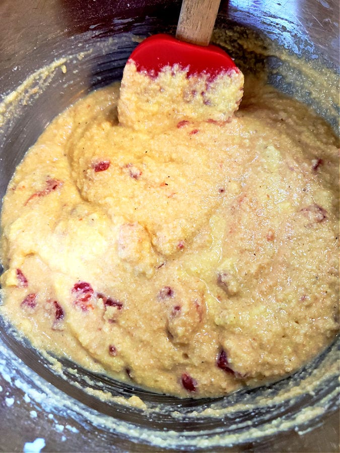 Stirring diced tomatoes into cornbread batter