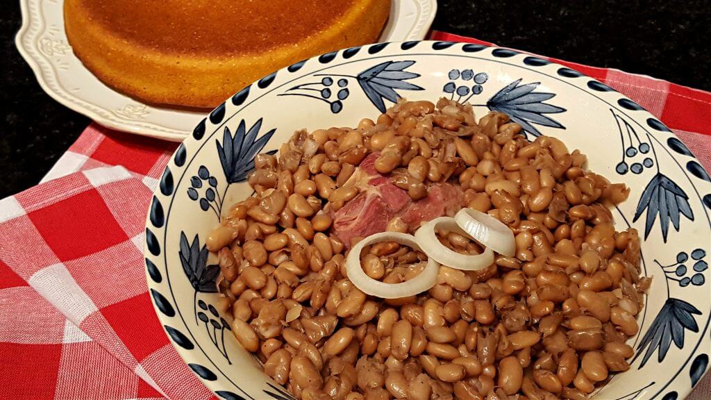 A bowl of pinto beans with a cake of cornbread