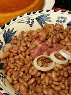 A bowl of pinto beans with a cake of cornbread
