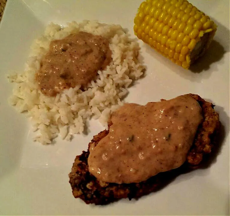 Country fried steak with gravy served with rice and corn on the cob