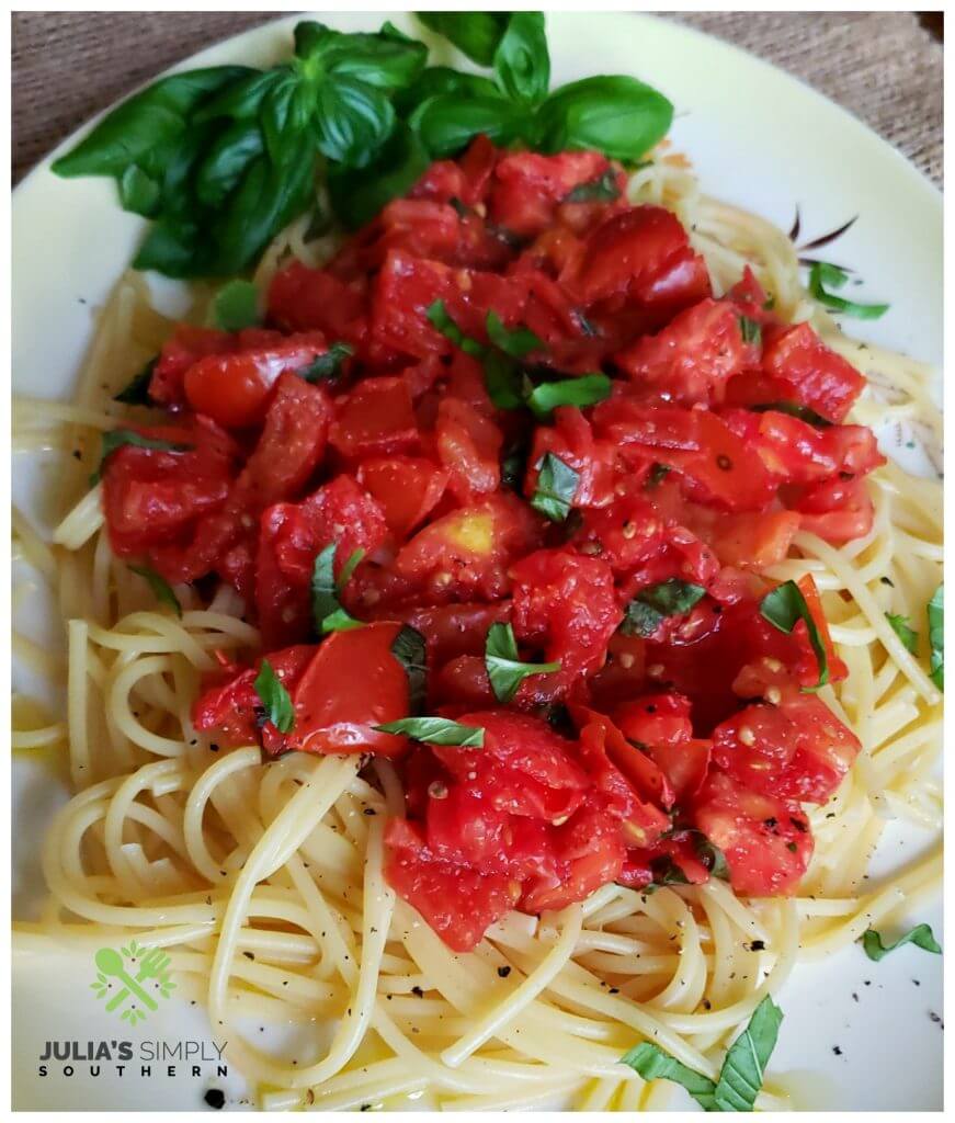 Beautiful platter of pasta topped with vine ripened stewed tomatoes and fresh basil, the perfect summer recipe