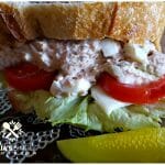 Southern Old Bay Tuna Salad with Duke's Mayonnaise on a glass salad plate with dill pickle spears