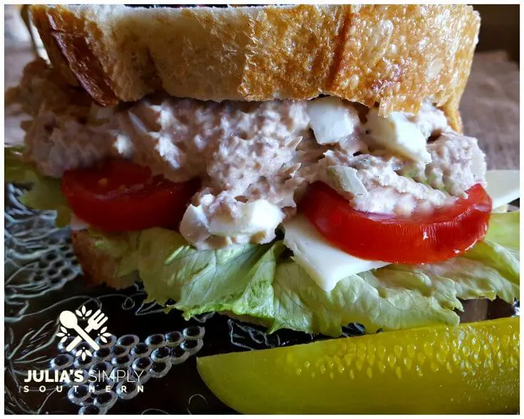 Southern Old Bay Tuna Salad with Duke's Mayonnaise on a glass salad plate with dill pickle spears