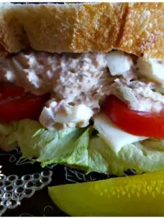 Southern Old Bay Tuna Salad with Duke's Mayonnaise on a glass salad plate with dill pickle spears