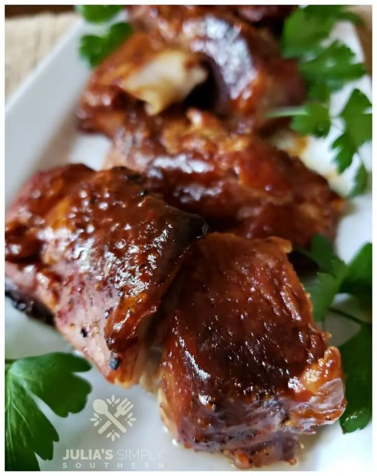 Tender baked pork country style ribs with barbecue sauce glaze on a white rectangle platter