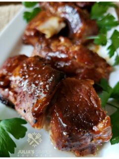 Tender baked pork country style ribs with barbecue sauce glaze on a white rectangle platter