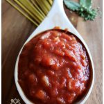 Homemade tomato Sauce is a wood ladle sitting on a wooden cutting board