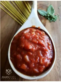 Homemade tomato Sauce is a wood ladle sitting on a wooden cutting board