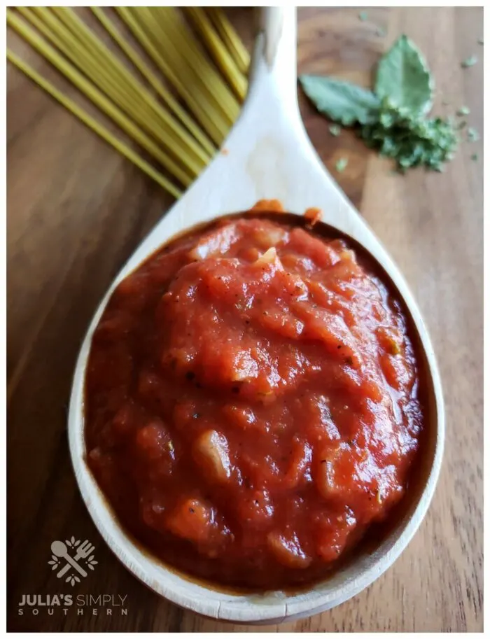 Homemade tomato Sauce is a wood ladle sitting on a wooden cutting board