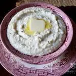 Best Southern style Grits in a red and white bowl with a pat of butter on top