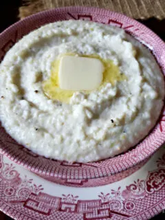 Best Southern style Grits in a red and white bowl with a pat of butter on top